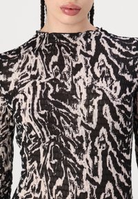 Black and beige long-sleeve top featuring a textured animal print pattern, with a high neckline and a fitted shape.