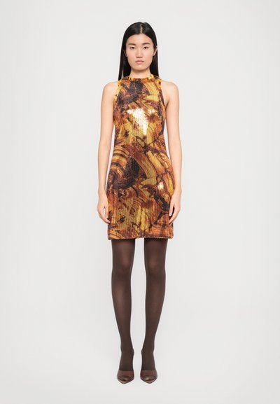 Ärmelloses Minikleid mit einem Paillettenmuster in Orange- und Brauntönen, ausgestattet mit einem hohen Kragen und einer figurschmeichelnden Silhouette. Trägt dazu braune Strumpfhosen und High Heels.