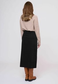 Fustă midi neagră cu talie ajustată. Asortată cu un pulover moale, roz deschis. Botine maronii până la genunchi. Textură netedă, design simplu.