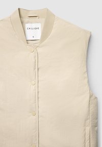 Beige gesteppte Weste mit rundem Ausschnitt, Druckknöpfen und glatter Textur. Im Inneren befindet sich ein Etikett mit der Aufschrift 'CALLIOPE'.