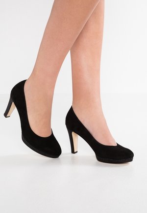 Tacchi alti in pelle scamosciata nera con punta chiusa e una texture morbida. Presentano un tacco slanciato di colore chiaro e una silhouette arrotondata.