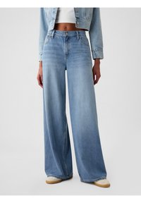Jasnoniebieskie dżinsy z szerokimi nogawkami i wysokim stanem, wykonane z denimu. Posiadają zapięcie na guzik i pięć kieszeni. Gładka faktura, swobodny krój.