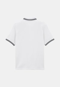 Chemise polo blanche en tissu texturé, à manches courtes, avec un col rayé noir et blanc. Design simple et épuré sans embellissements supplémentaires.