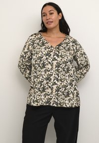 Langärmlige Bluse in Cremetönen mit schwarzem und grünem abstraktem Blumenmuster, mit V-Ausschnitt und lockerem, entspanntem Schnitt. Glatte Stofftextur.