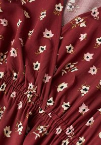 Červená látka s malým růžovým a černým květinovým potiskem, zdobená nabráním pro texturu a strukturu. Hladký, lehký materiál.