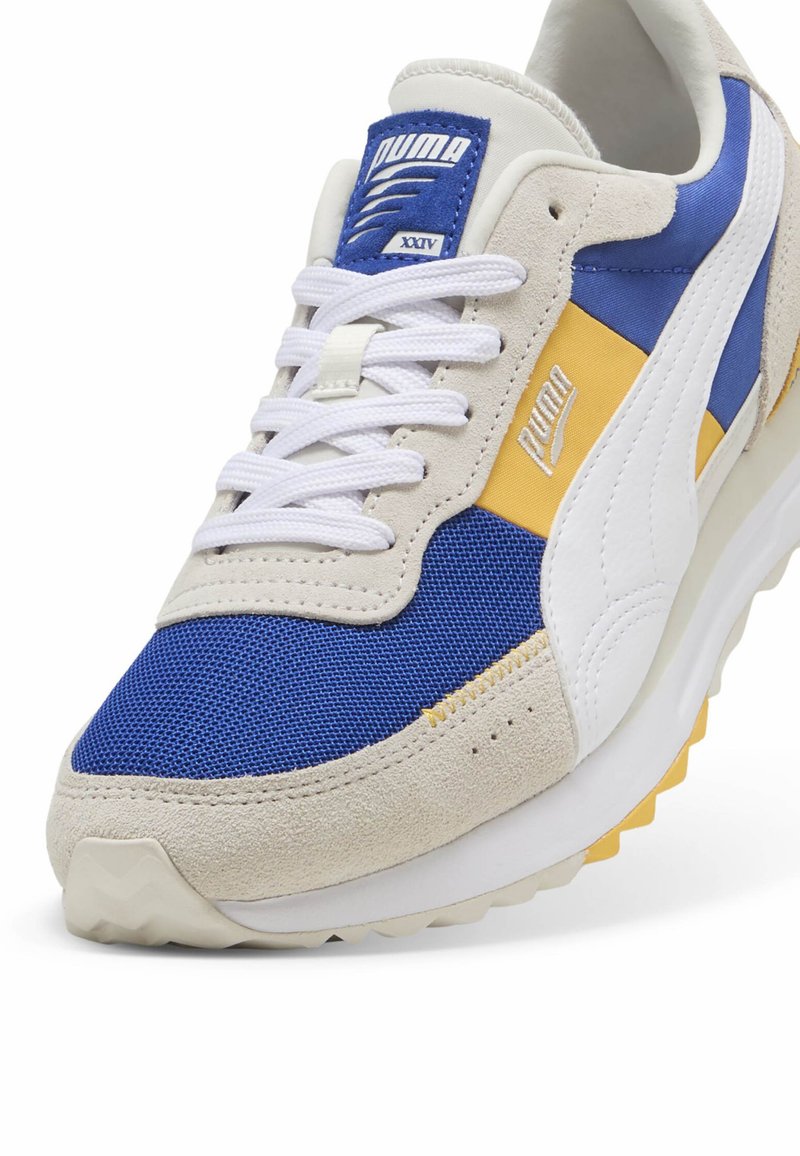 Sneakers Puma z niebieskiej siateczki i beżowego zamszu, z żółtymi i białymi akcentami. Grube białe sznurówki i teksturowana podeszwa.