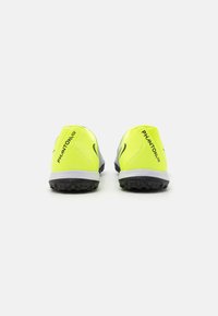 Helle gelbe Sportschuhe mit glatter Oberfläche, runder Form, schwarzen strukturierten Sohlen und "PHANTOM"-Markierung an den Seiten.