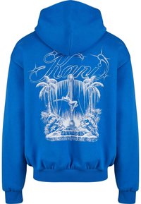 Modra kapuca z belim grafičnim dizajnom, ki vključuje palme, plesalko na drogu in besedo "Kani" v stilizirani pisavi.