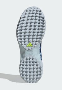 Shoe sole features a white rubber base with circular, raised studs for traction, highlighted by a green accent displaying "TORSION SYSTEM."