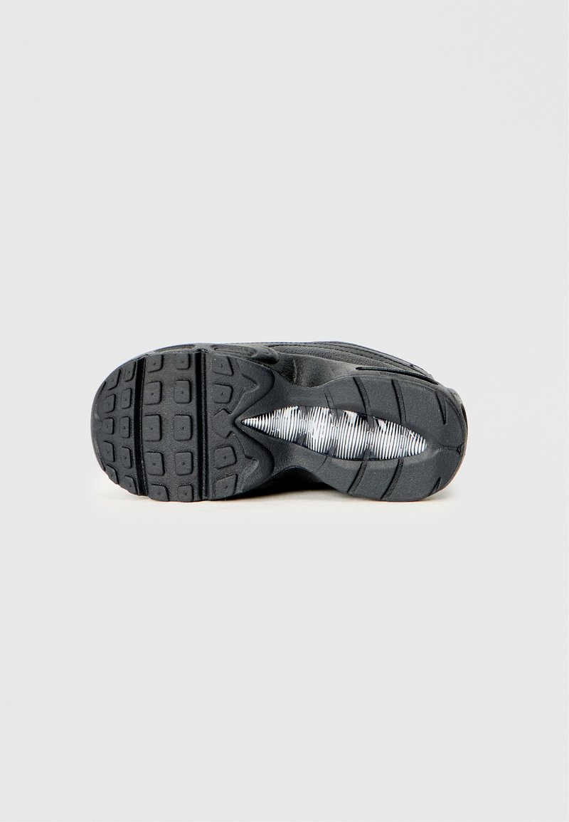 Semelle extérieure noire de sneaker avec un motif texturé et un élément de rembourrage blanc visible dans la zone de la semelle intermédiaire, sur un fond uni.