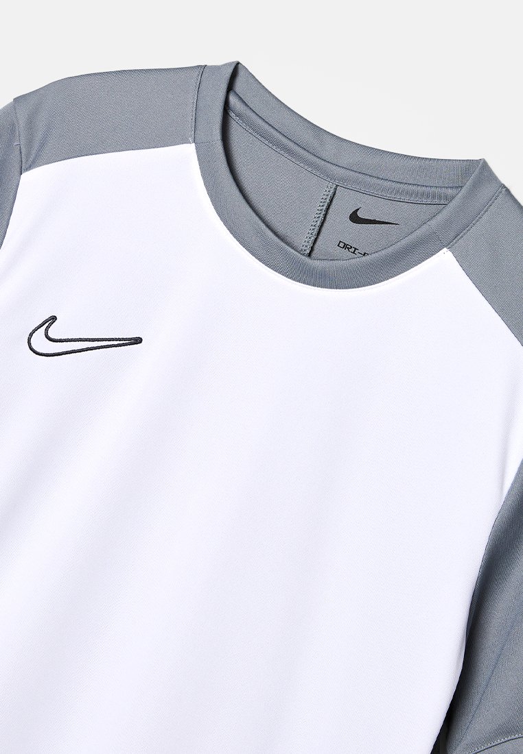T-shirt de sport blanc avec des manches raglan grises, arborant un logo Nike noir sur la poitrine et une texture lisse. Tissu synthétique léger.