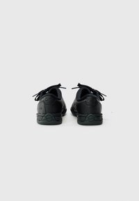 Schwarze Sportschuhe aus glattem Leder, mit runder Zehenpartie und strukturierten Akzenten. Verfügt über schwarze Schnürsenkel und ein Logo an der Ferse.