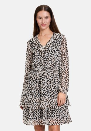 Schwarz-weißer gemusterter Kleid aus durchscheinendem Stoff, mit einem Rüschenausschnitt, elastischem Bund und mehrlagigem Rock. Langer Ärmel vorhanden.