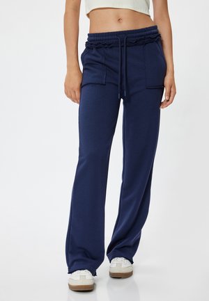 Marineblauwe sweatpants met een tailleband met trekkoord, twee voorzakken en een relaxte pasvorm. De stof lijkt zacht met een gladde textuur.