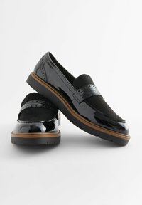 Mocassini in pelle verniciata nera con una fascia in suede nero testurizzato, caratterizzati da dettagli perforati e una suola robusta in cuoio color tan.