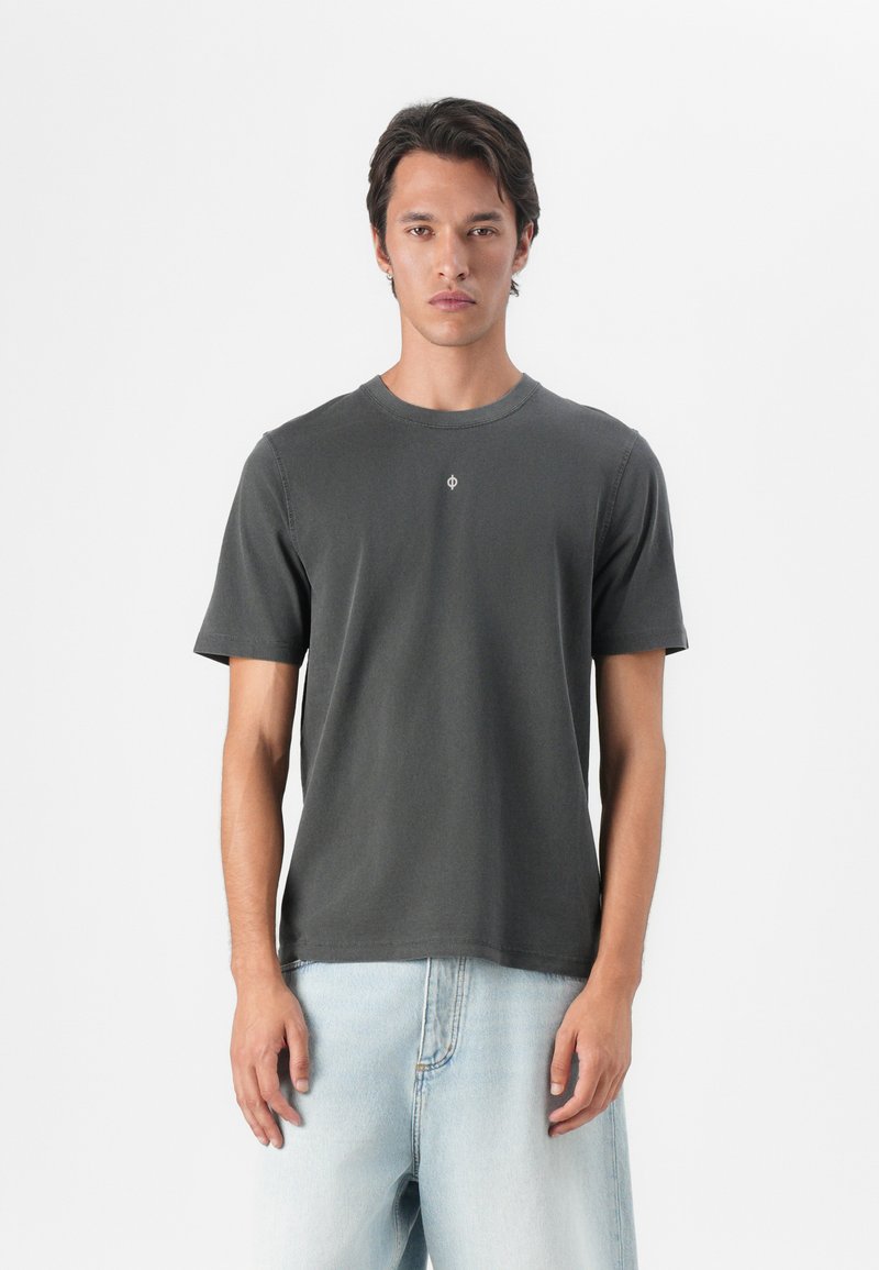 Dunkelgraues Baumwoll-T-Shirt mit Rundhalsausschnitt, kurzen Ärmeln und einem kleinen Logodetail auf der Brust, kombiniert mit hellblauen Jeans.