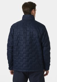 Námořnická prošívaná bunda s stojáčkovým límcem a texturovaným povrchem. Lehký materiál s geometrickým vzorem. Pohled zcela zezadu.