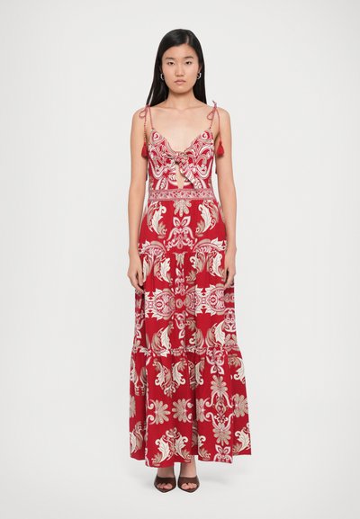 Robe maxi rouge avec des motifs floraux et paisley, bretelles spaghetti ajustables, et un lien au niveau du buste. Ourlet uni et tissu doux.