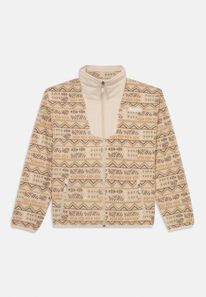 Bežna flis jakna s vzorcem v rjavi, peščeni in gorčični barvi. Ima visok ovratnik in zadrgo ter stranske žepe.