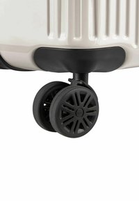 Angolo della valigia rigida con base nera in plastica e due ruote nere con design a raggi per manovrabilità e stabilità.