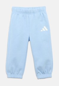 Ανοιχτό μπλε φόρμα με ελαστική μέση και μανσέτες, με λευκό λογότυπο Adidas στο αριστερό μέρος. Κατασκευασμένη από απαλό υλικό, απλός σχεδιασμός.