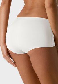Slip bianco hipster con una texture liscia, design senza cuciture e copertura moderata. Presenta un morbido e flessibile elastico in vita e nessuna cucitura visibile.