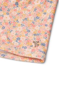Blommönstrad tyg i pastellrosa, med små flerfärgade blommor. Inkluderar en märkesetikett med grå text i nedre högra hörnet.