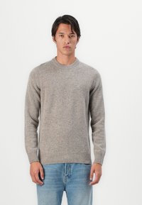 Suéter cinza texturizado com gola redonda e mangas longas, feito de uma mistura de lã. Combinado com jeans de algodão de tom azul claro.