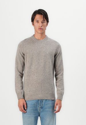 Grijze textuurtrui met een ronde halslijn en lange mouwen, gemaakt van een wolmix. Gecombineerd met lichtblauwe denim jeans.