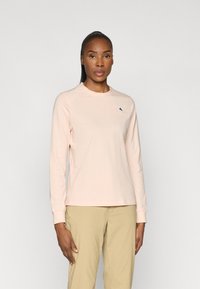 Lange mouwen shirt van lichtroze katoen, met een ronde hals en een klein blauw berglogo op de linkerborst. Zachte textuur, ontspannen pasvorm.