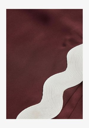 Bordeaux stof med en glat tekstur, der har en kontrasterende hvid bølget kant med et ribbet design langs den ene side.