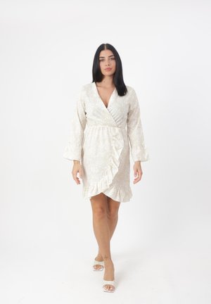 Vestido floral tipo wrap en color crema con dobladillo y mangas con volantes. Presenta un escote en V profundo y una cintura ajustada. Tejido ligero con una textura sutil.