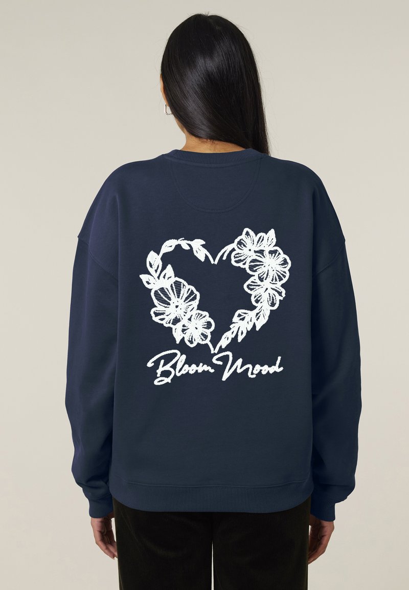 Sweatshirt bleu marine avec un design de cœur floral blanc et le texte "Bloom Mood" au dos. Manches longues, poignets et ourlet côtelés.