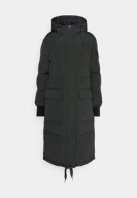 Lång svart pufferjacka med huva, frontdragkedja, dragskor och två påsydda fickor. Innehåller en quiltad textur och ribbade ärmslut.