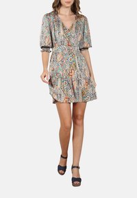 Robe à motif floral en tissu léger, avec des manches bouffantes, un col en V et une jupe à volants. Les couleurs incluent le turquoise, l'orange et le noir.