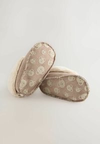 Chaussons marron avec un intérieur doux et duveteux, ornés d'un imprimé ours en peluche beige sur le tissu extérieur. Forme arrondie, bords cousus.