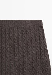 Dunkelbrauner Strickrock mit einem strukturierten Zopfmuster, einem gerippten Bund und einem weichen, gemütlichen Erscheinungsbild.