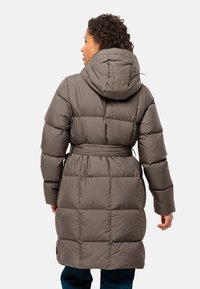 Olijfgroen pufferjack met capuchon, ceintuur in de taille en een geborduurd textuur. Heeft lange mouwen en valt tot halverwege de kuit.