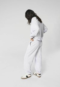 Grå sweatshirt og sweatpants sæt, lavet af blødt stof. Sættet har en afslappet pasform, ribbede manchetter og sidelommer. Parret med sneakers.