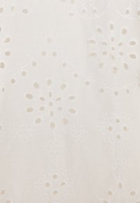 Tessuto bianco con motivi floreali ricamati, caratterizzato da dettagli ritagliati e una consistenza liscia, che offre un design delicato e intricato.