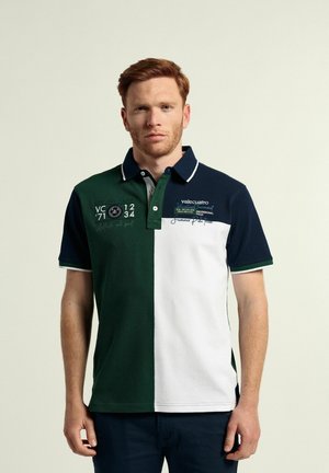 Camisa polo con bloques de color verde, azul marino y blanco, material de algodón, cuello con botones y detalles de logotipo y texto bordados.