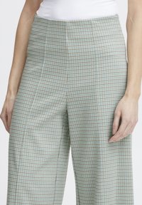 Pantalons à carreaux bleu clair à taille haute, avec des jambes larges, en tissu texturé et présentant des coutures verticales pour un aspect ajusté.