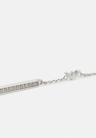 Bracciale d'argento con una barra rettangolare di pietre trasparenti, collegata a una catena. Include un dettaglio hardware distintivo alla chiusura.