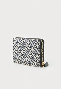 Textured fabric wallet in cream with dark blue geometric patterns, featuring a gold zipper and black accent. Compact square shape.