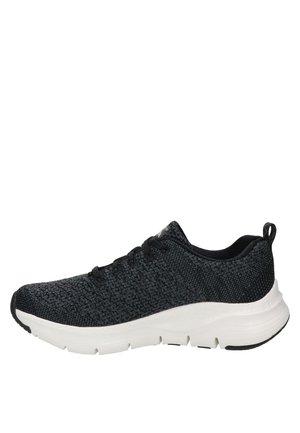 Chaussure de sport noire avec un dessus en maille texturée, un design à lacets et une semelle chunky blanche. Présente une silhouette basse et des coutures sur les côtés.