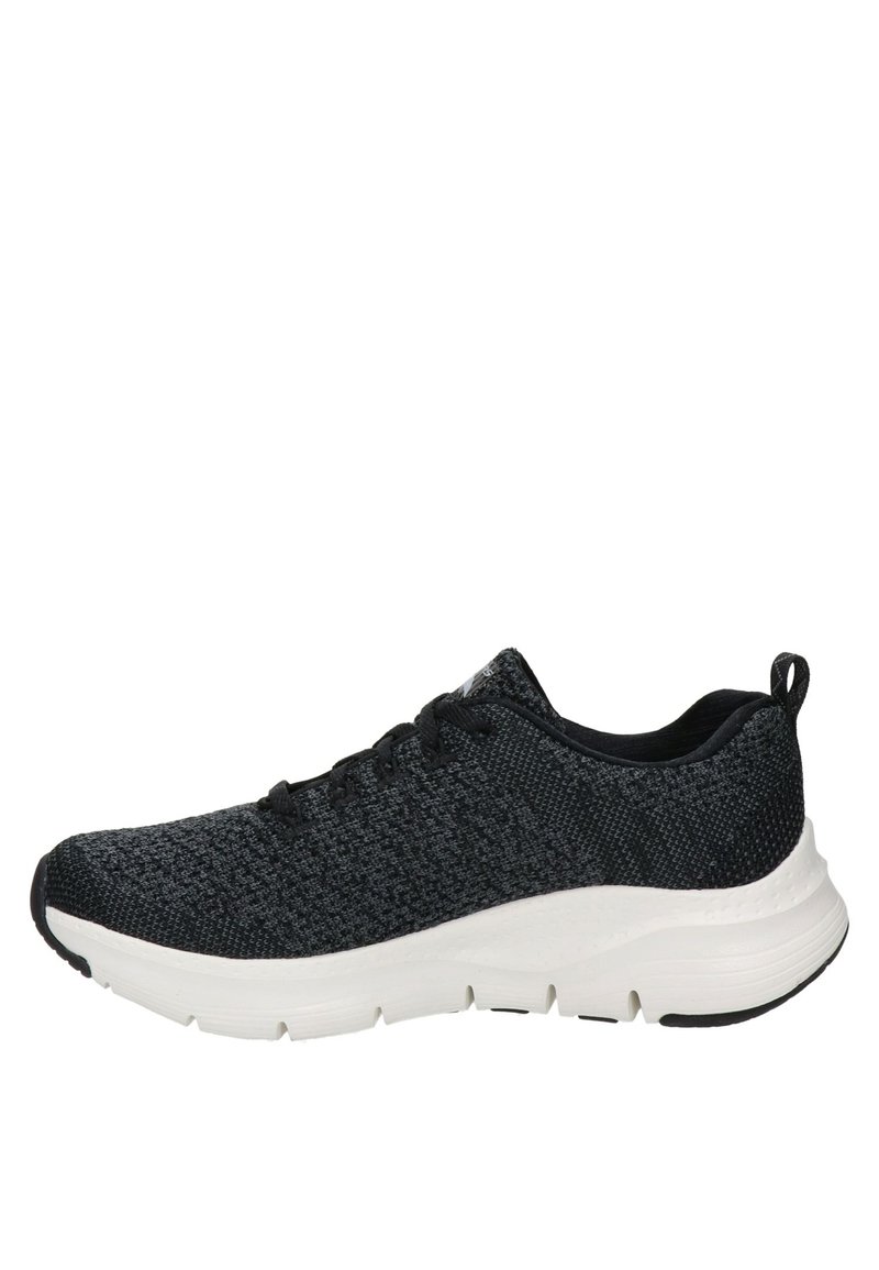 Chaussure de sport noire avec un dessus en maille texturée, un design à lacets et une semelle chunky blanche. Présente une silhouette basse et des coutures sur les côtés.
