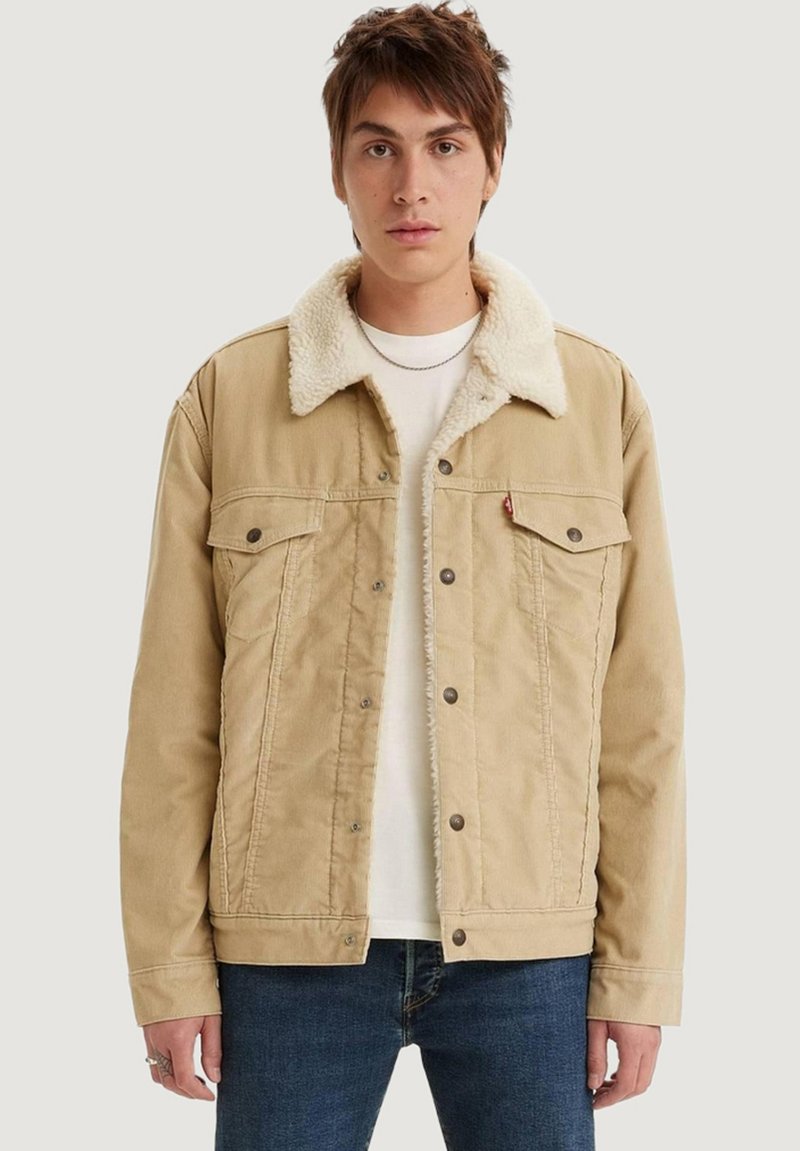 Chaqueta de mezclilla color crema con un cuello de borreguito sintético beige, que cuenta con dos bolsillos en el pecho, botones a presión y un corte recto.