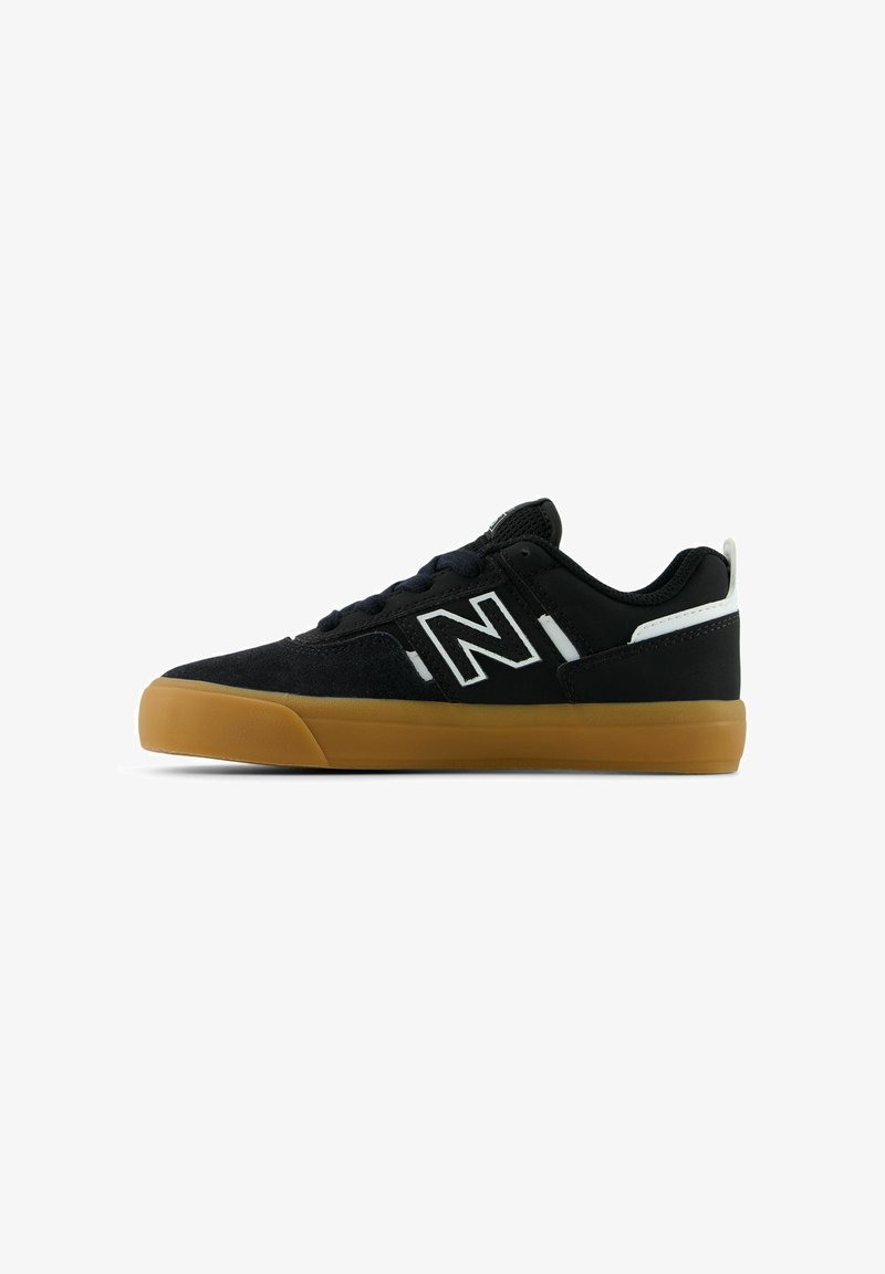 Baskets basses noires avec semelle en gomme, accent blanc au talon et grand logo blanc "N" sur le côté.