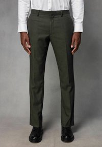 Olivengrøn skræddersyet bukser i en struktureret kvalitet, slim fit, glat front og bælteløkker, parret med sorte dress sko.