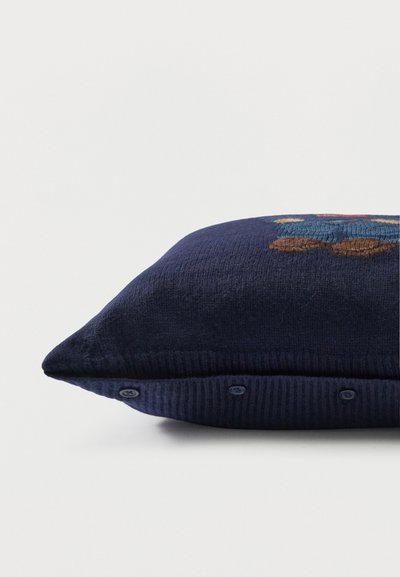 Μαξιλάρι πλεκτό σε ναυτικό μπλε χρώμα με κούμπωμα κουμπιού και μερικό κεντητό σχέδιο αρκουδάκι σε λευκό φόντο.